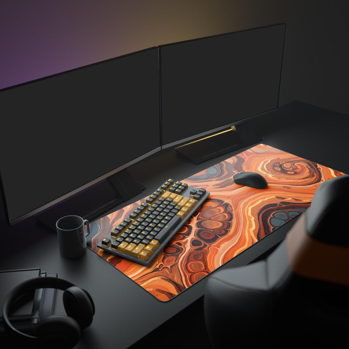 Orange and brown fluid pour desk mat on a dark desk with two monitors, a black and yellow keyboard, mouse and mug.