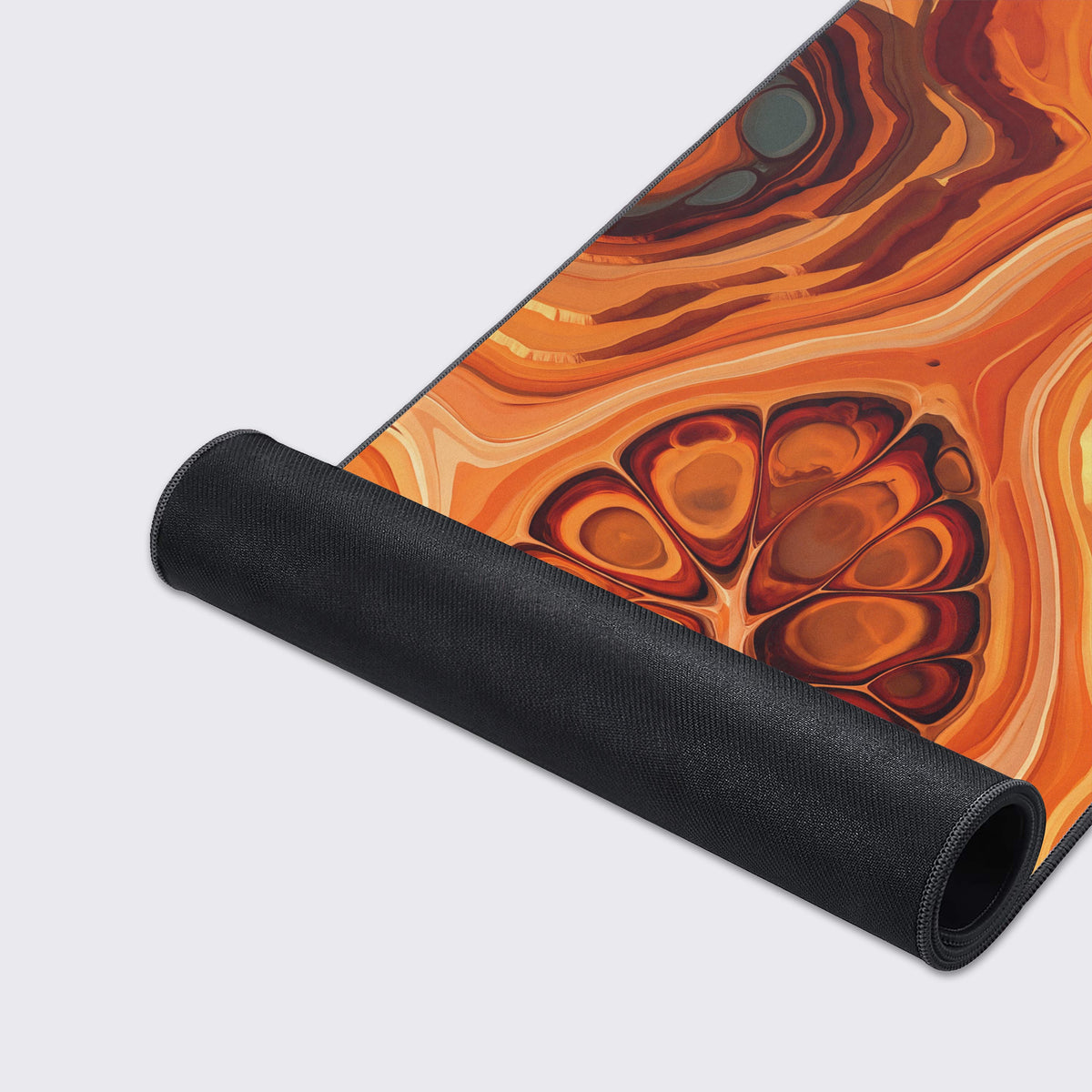 Desk mat partly rolled up to show its black rubber underside and the orange and rust fluid pour cells on top.