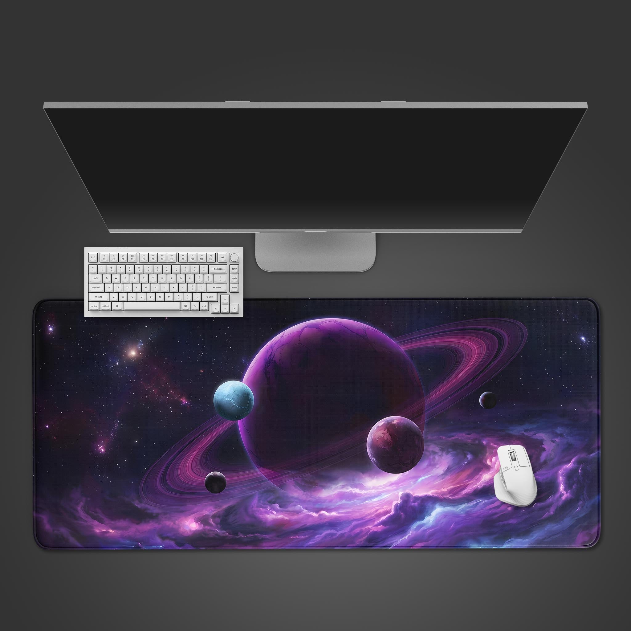 A top-down view of the Orbital Command Gaming Desk Mat, featuring a purple ringed planet, placed under a modern monitor, white keyboard, and mouse. - Epic Design Pads & Mousepads