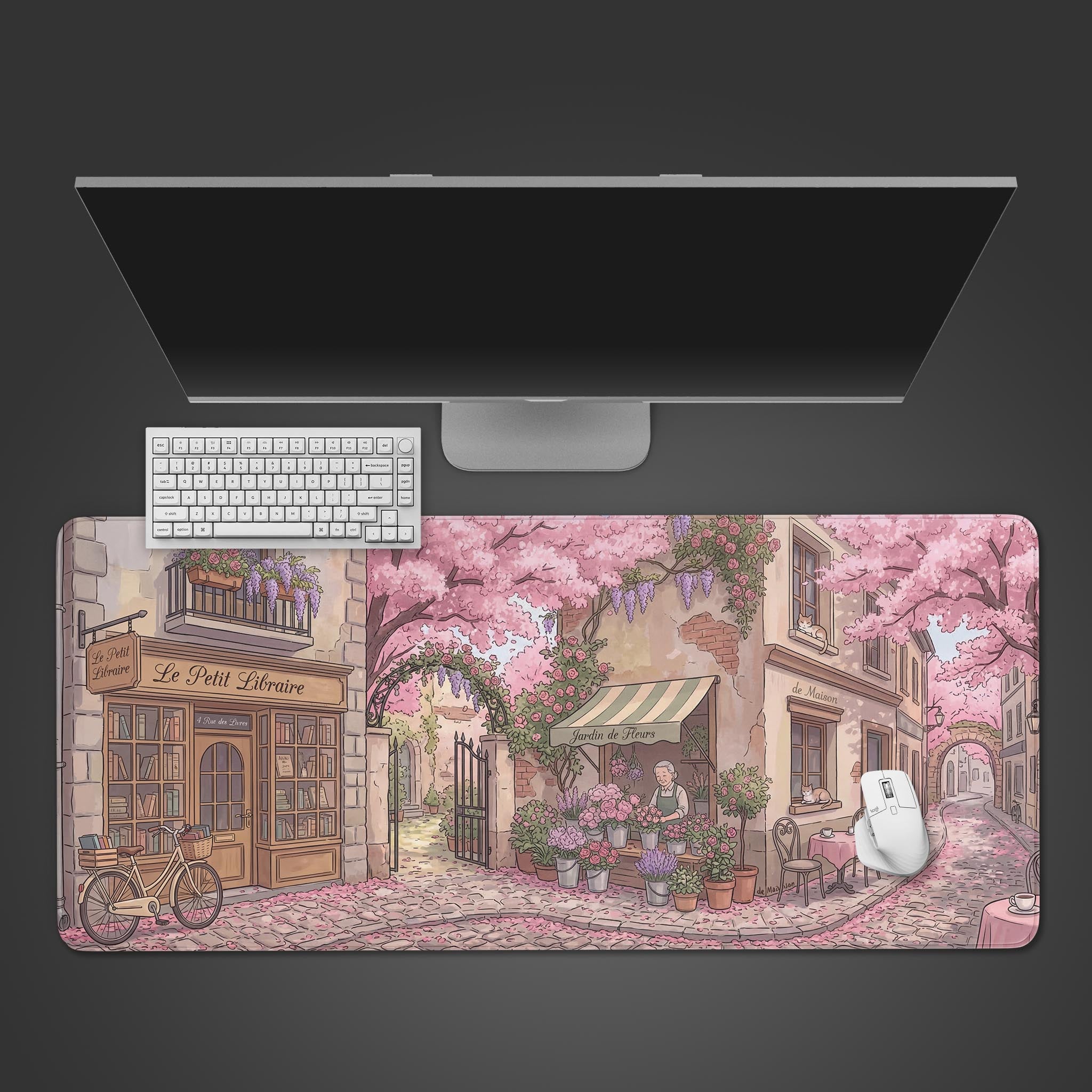 A top-down view of the Parisian Spring gaming desk mat, featuring a pink floral bookshop scene with a white keyboard and mouse on top. - Epic Design Pads & Mousepads