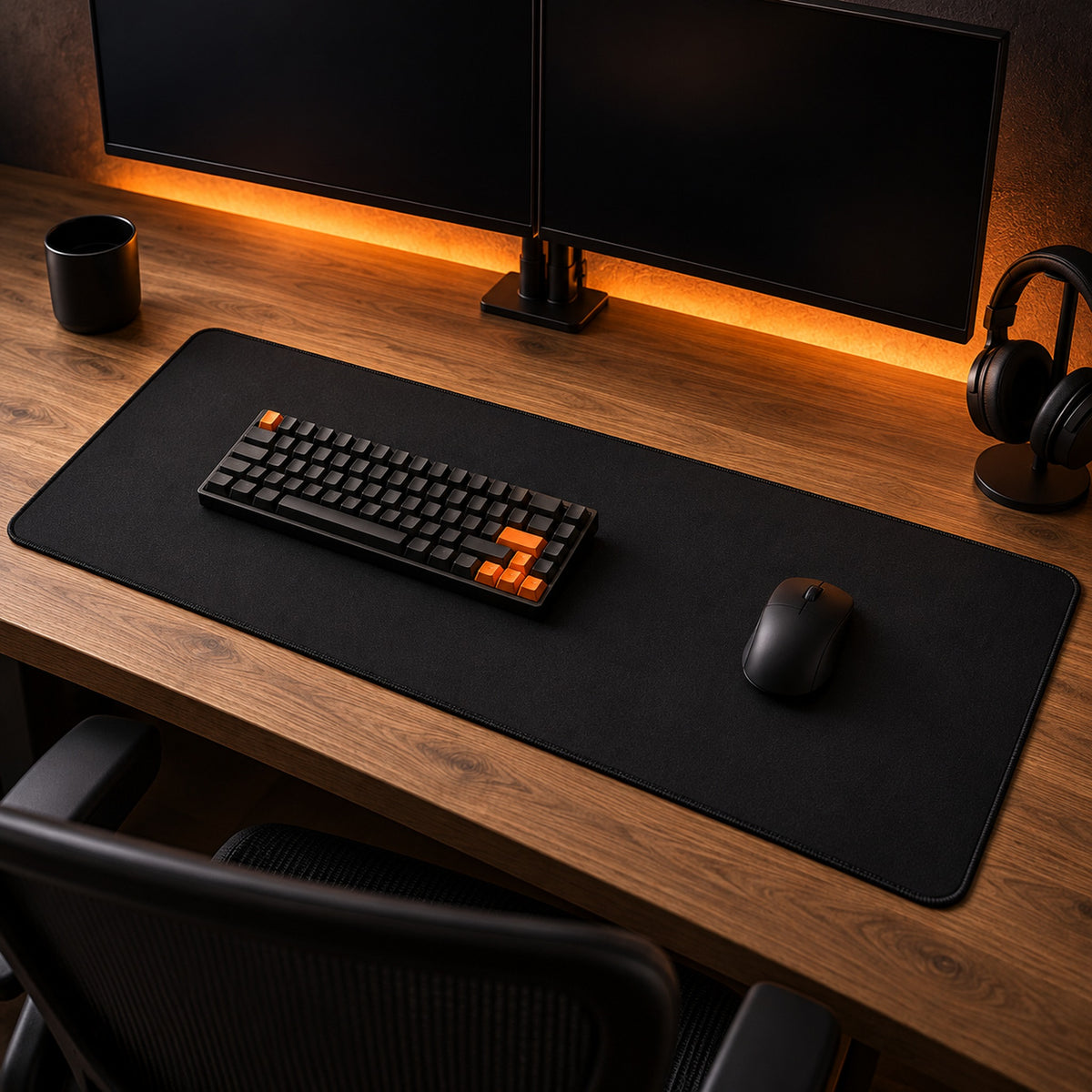 Pure Black Desk Pad on a walnut desk at night under orange backlight, with a black keyboard and mouse