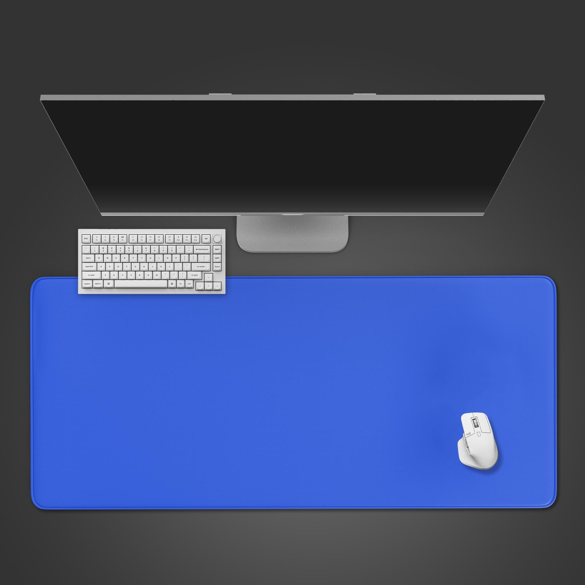 Top-down view of the Royal Blue gaming desk mat on a dark surface, shown with a white wireless keyboard and mouse, and a sleek monitor. - Epic Design Pads & Mousepads