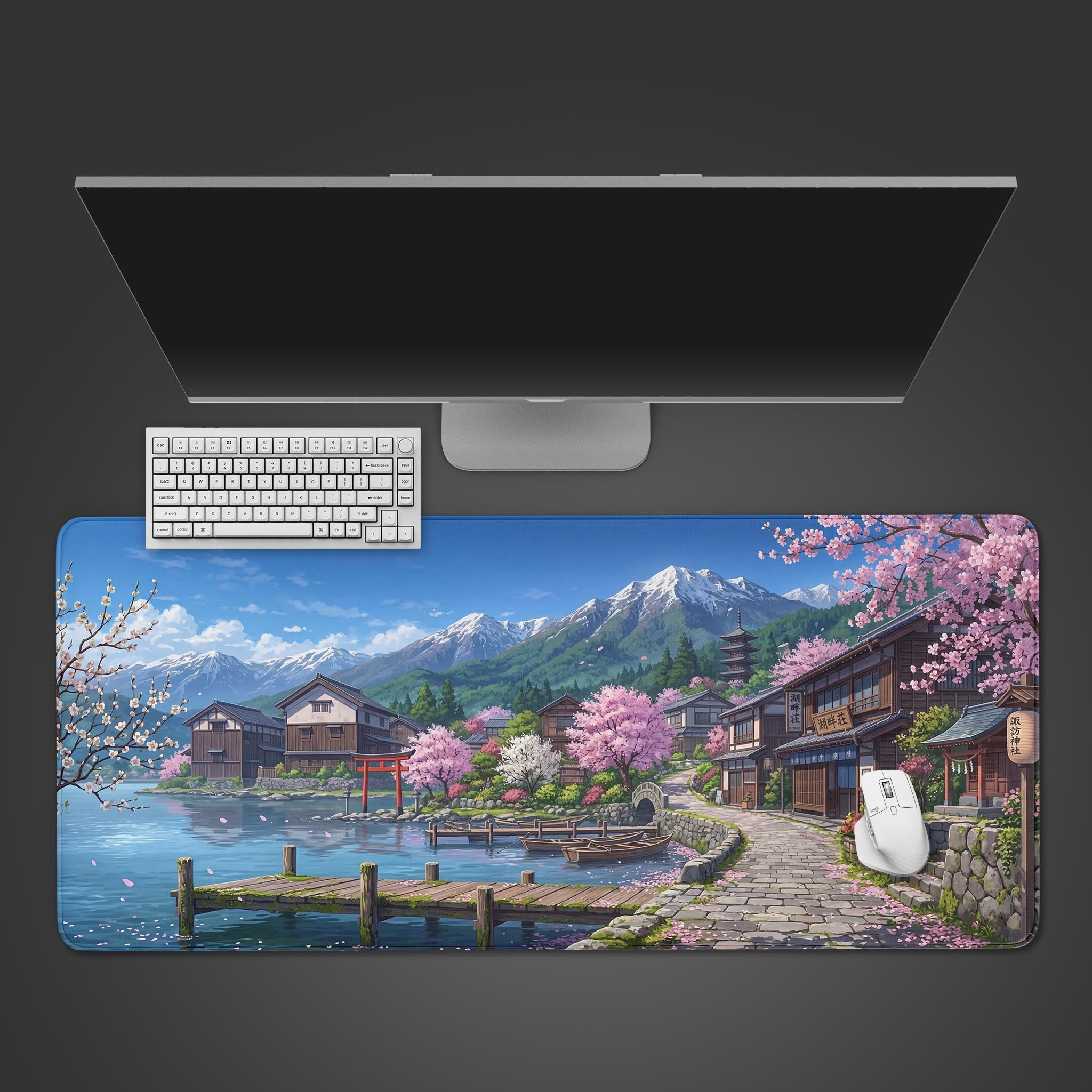 Top-down view of the Sakura Shores gaming desk mat with a white keyboard and mouse, placed below a large monitor, showcasing the serene Japanese village design. - Epic Design Pads & Mousepads