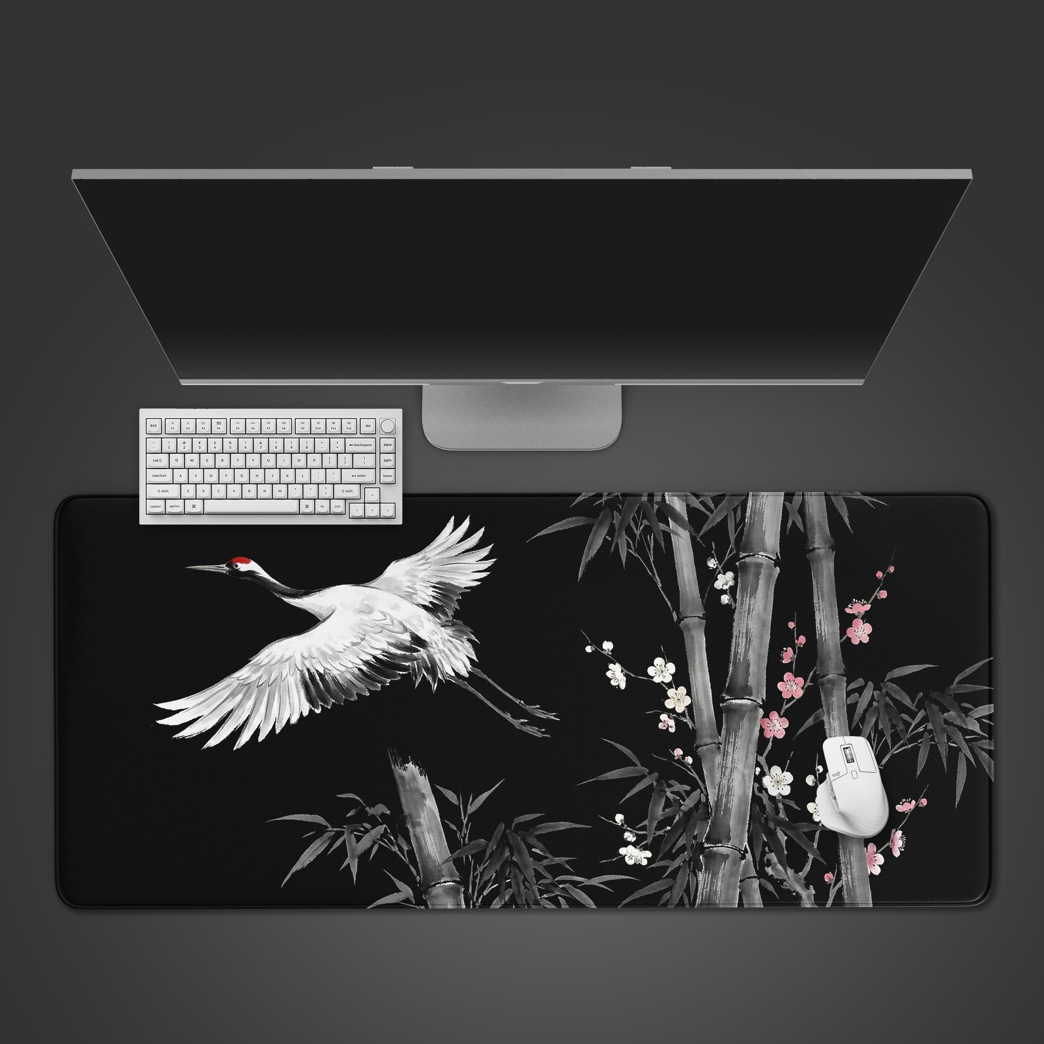 Top-down view of the Shadow Flight gaming desk mat featuring a Japanese ink wash crane and bamboo, shown with a white keyboard and monitor on a dark surface. - Epic Design Pads & Mousepads