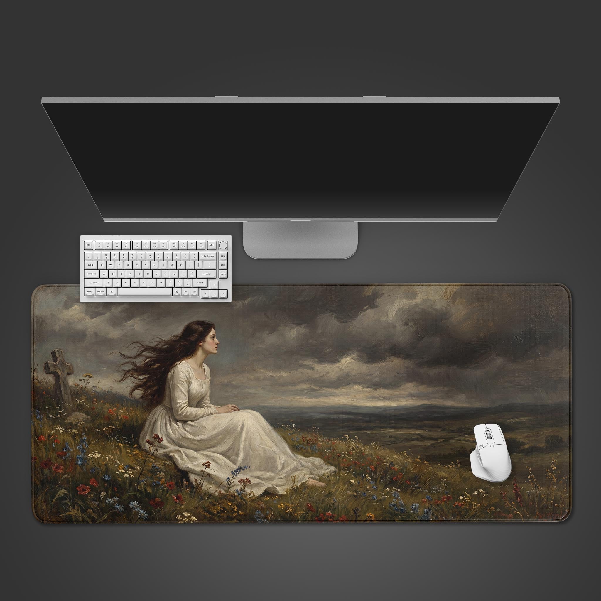 Top-down view of the Stormborn Grief gaming desk mat featuring a woman in a stormy landscape, shown with a white keyboard, mouse, and monitor on a dark surface. - Epic Design Pads & Mousepads