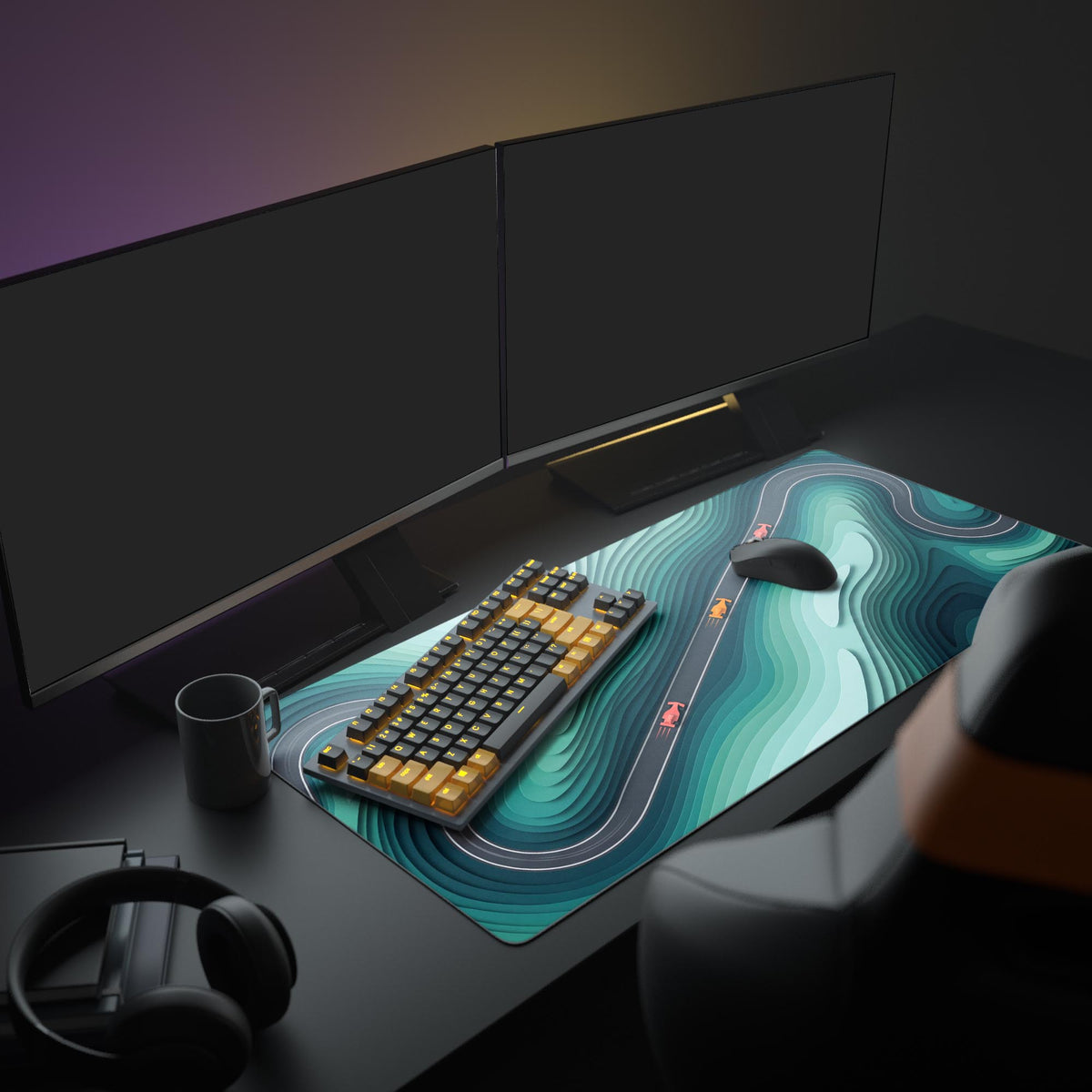 Teal topographic race track mat on a dark desk with two monitors, black and orange keyboard, mouse, mug and headphones