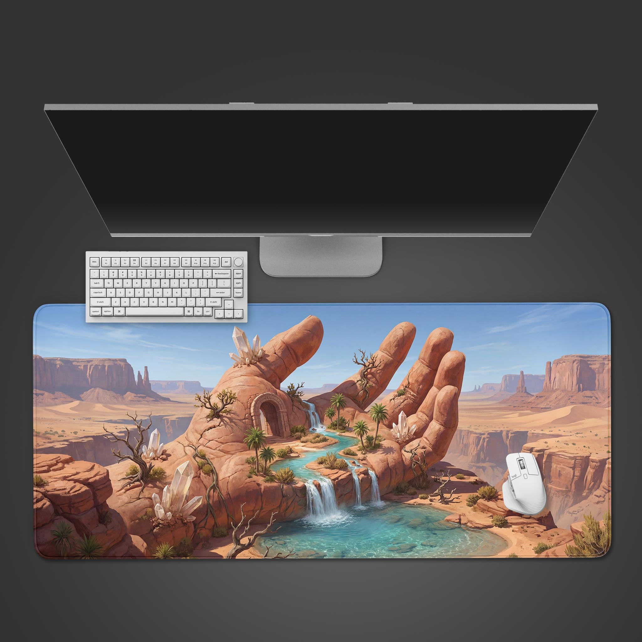 A top-down view of 'The Keeper's Palm' gaming desk mat showing the fantasy desert oasis design next to a white keyboard, mouse, and a large monitor on a dark background. - Epic Design Pads & Mousepads