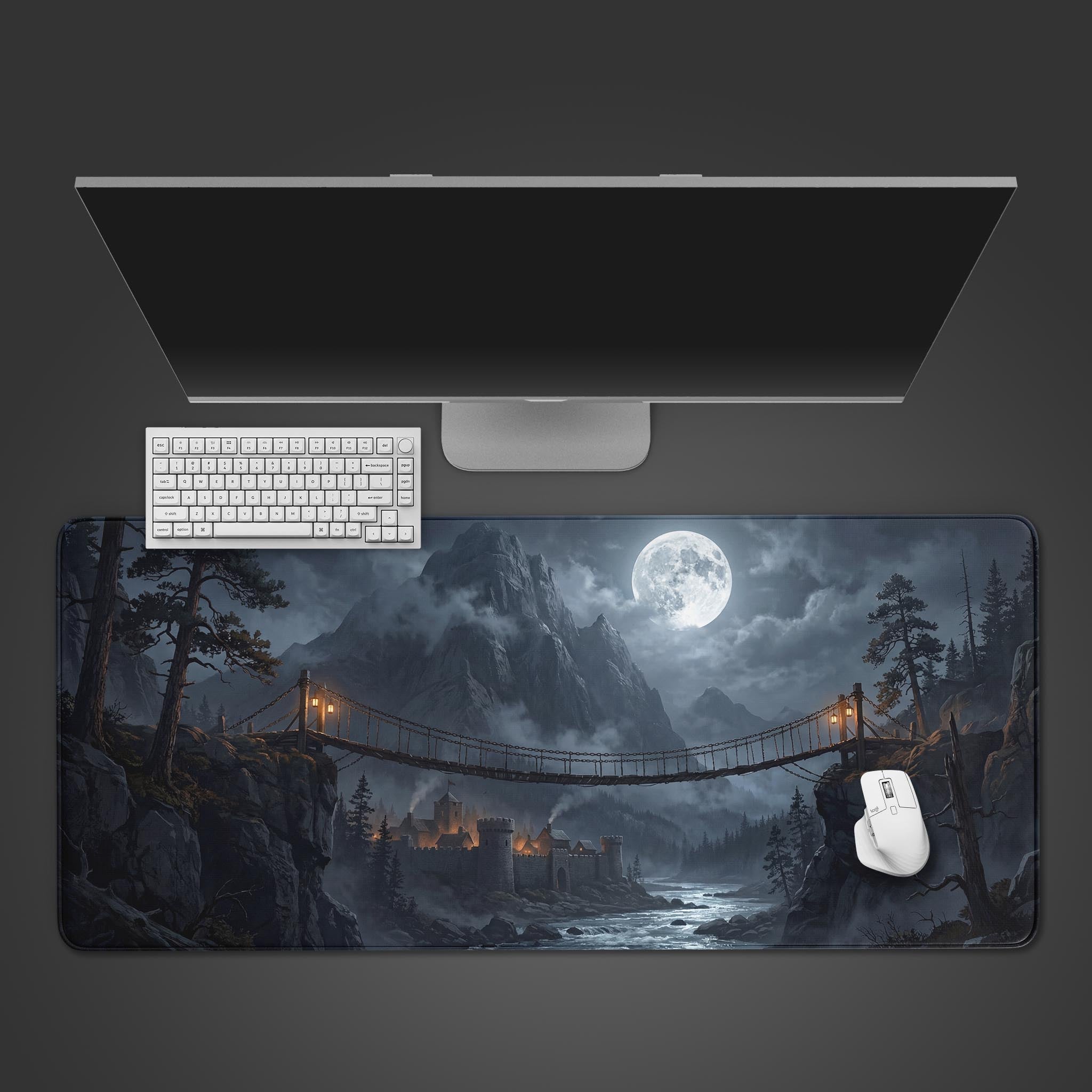 Top-down view of The Last Bridge gaming desk mat, showing a moonlit castle and bridge. A white keyboard and mouse are placed on the mat below a sleek monitor. - Epic Design Pads & Mousepads