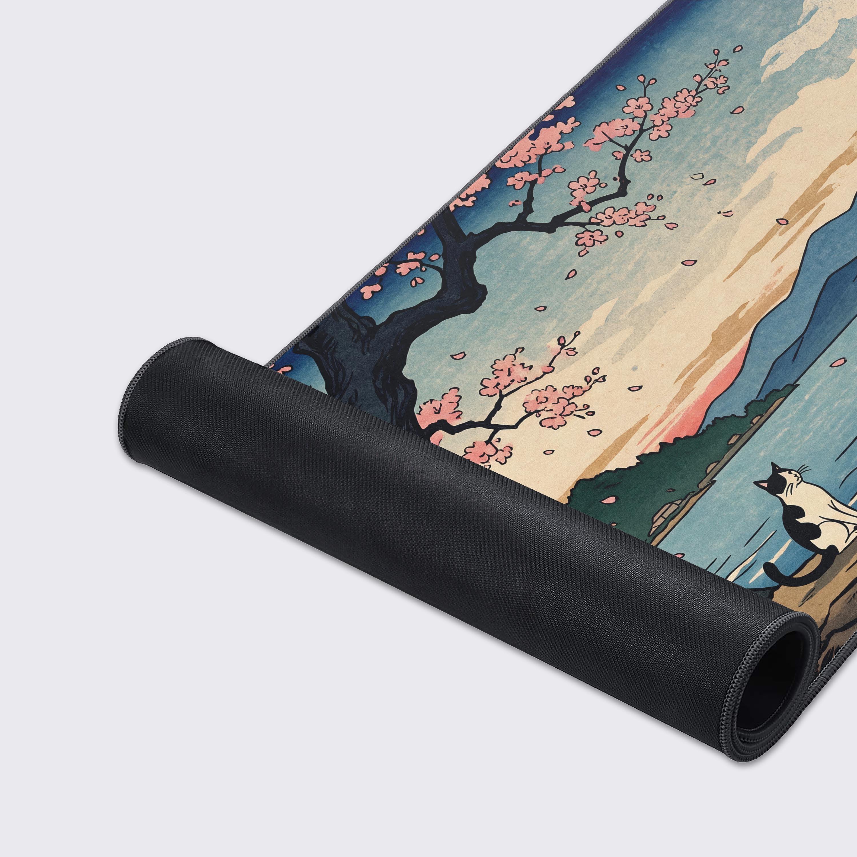 Tuxedo cat looking out over the stylized blue waves and mountains on the desk pad.