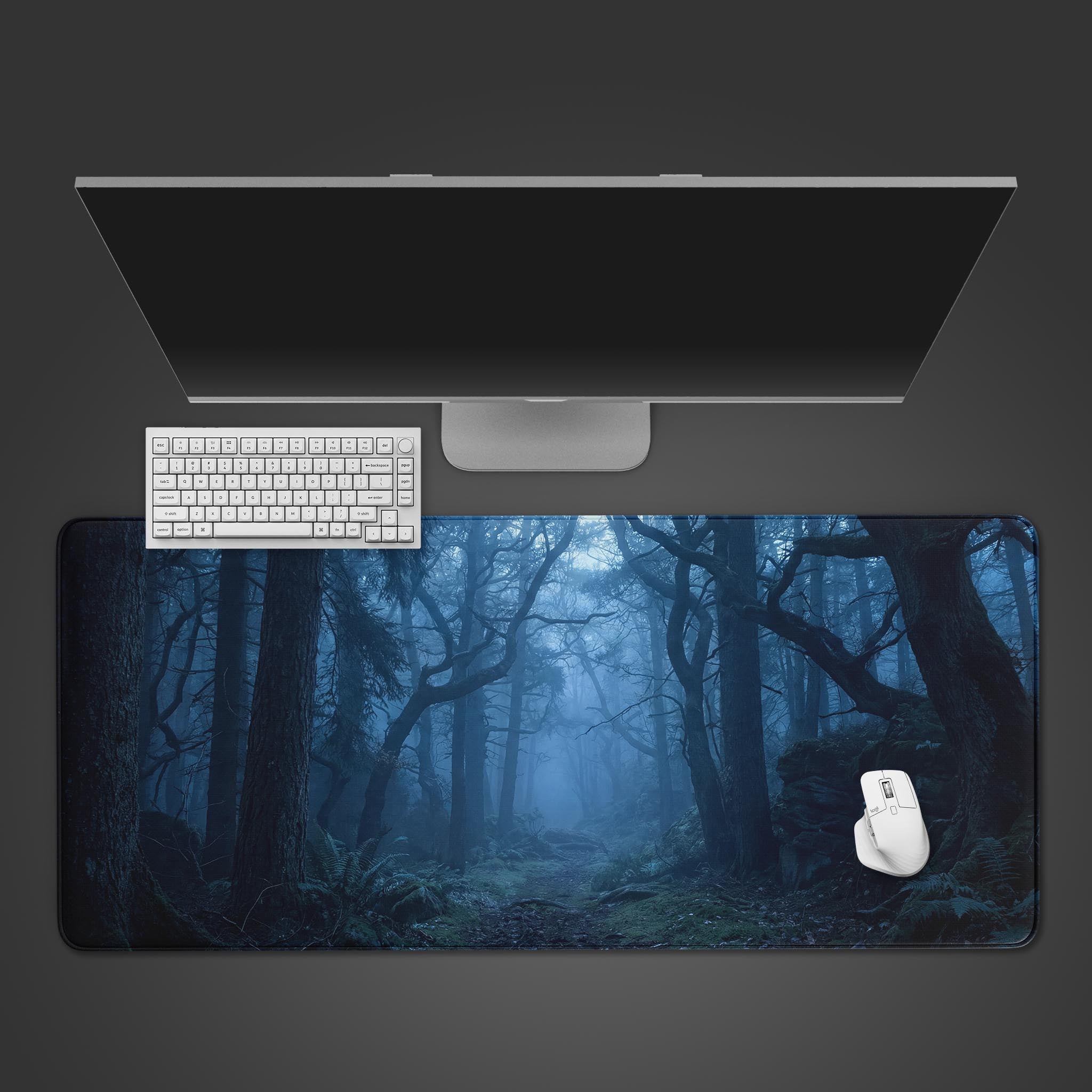Twilight Woods desk mat with a misty blue forest design, shown from a top-down view with a black keyboard and mouse. - Epic Design Pads & Mousepads