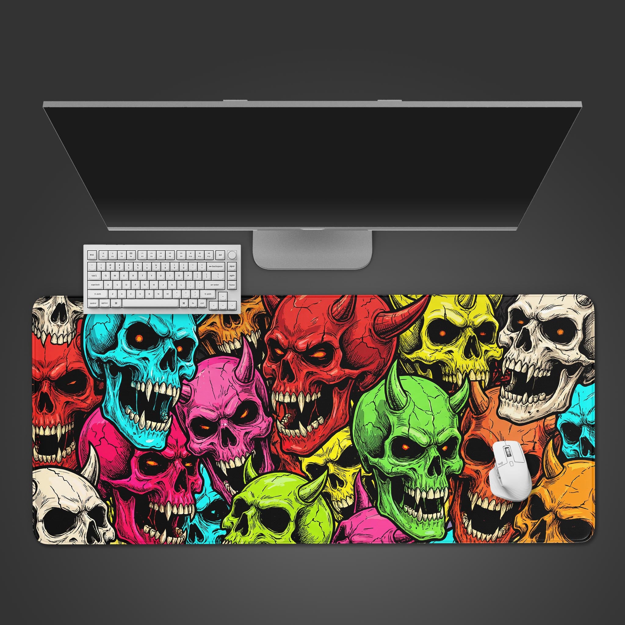 A top-down view of the Vibrant Souls gaming desk mat featuring colorful skulls, with a white keyboard and mouse placed on it under a large monitor. - Epic Design Pads & Mousepads