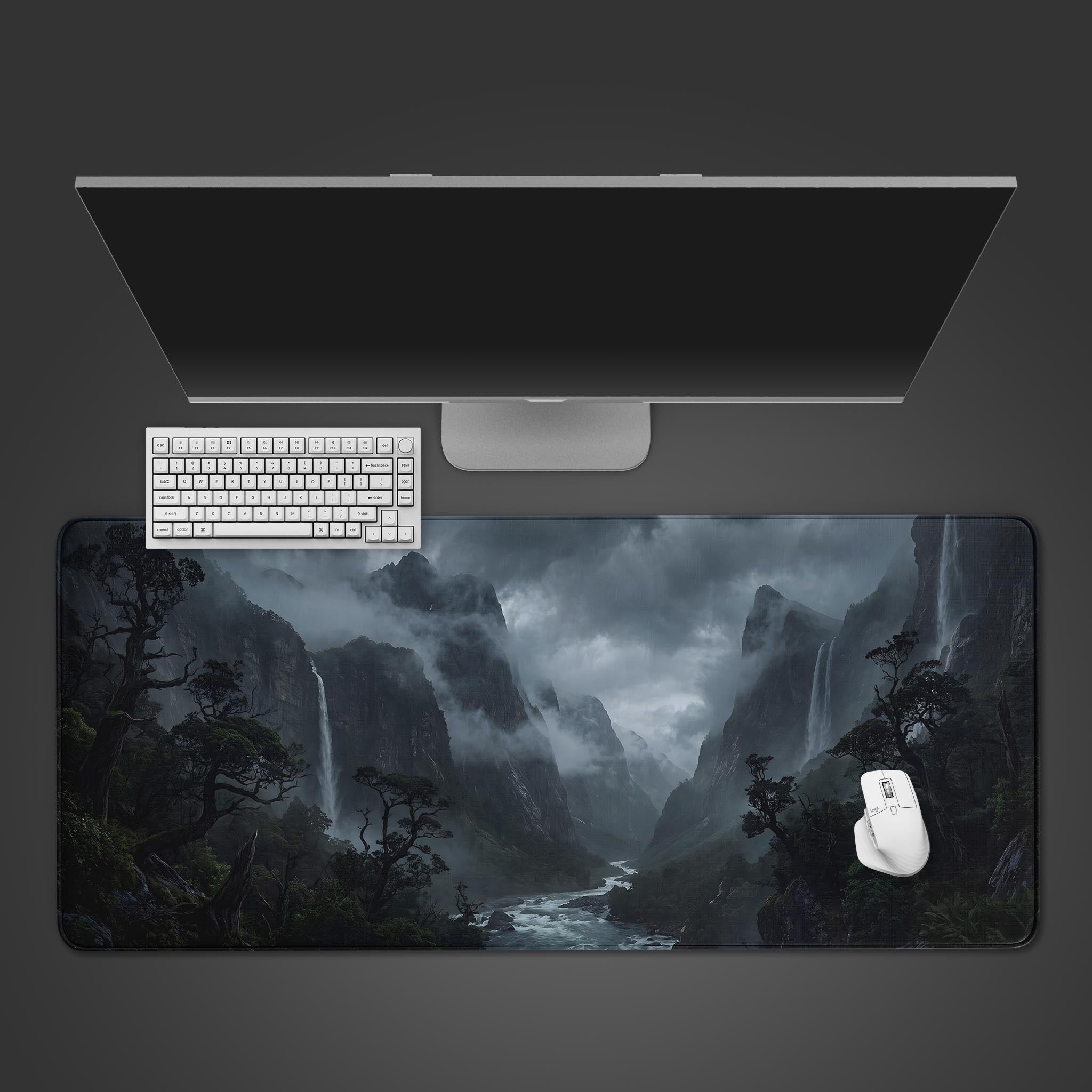 A desk mat displaying a dark, misty mountain gorge with cascading waterfalls and a winding river.