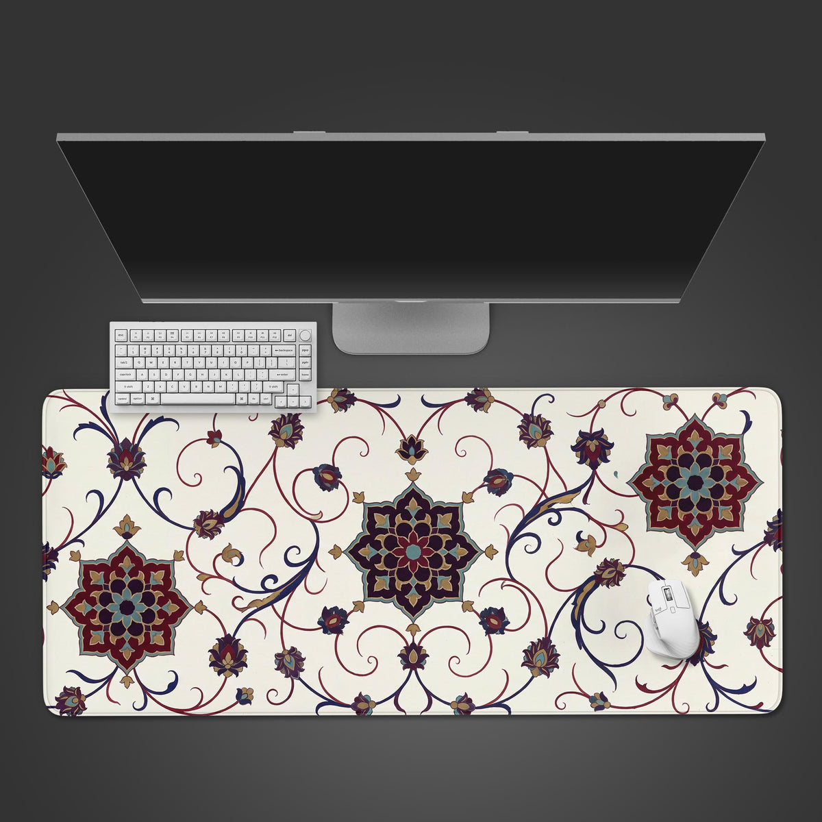 Top-down white abstract vintage desk mat with crimson and navy floral medallions, a monitor, white keyboard and mouse