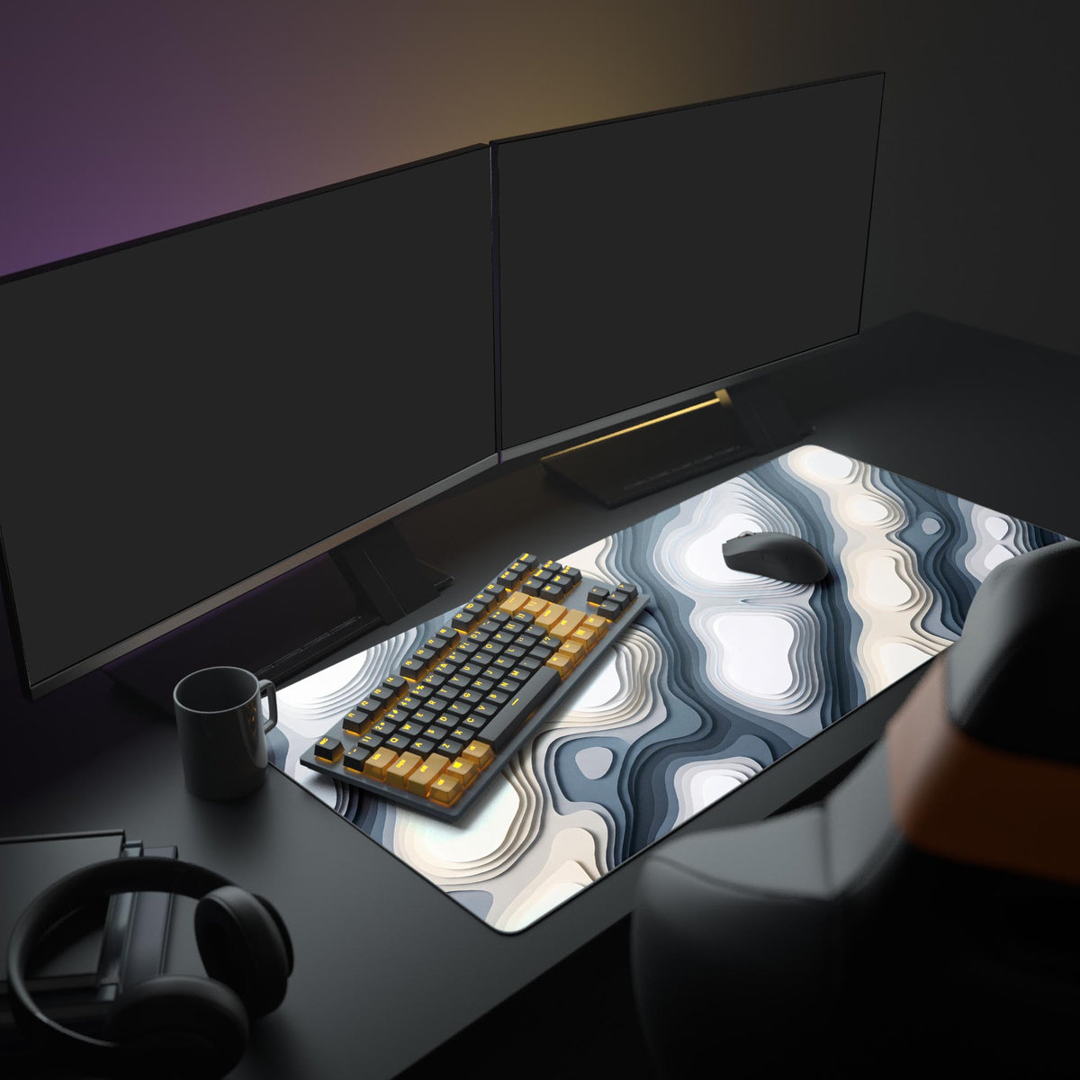 Layered white, beige and gray contour desk mat on a dark desk with two monitors, a black and amber keyboard, mouse and mug