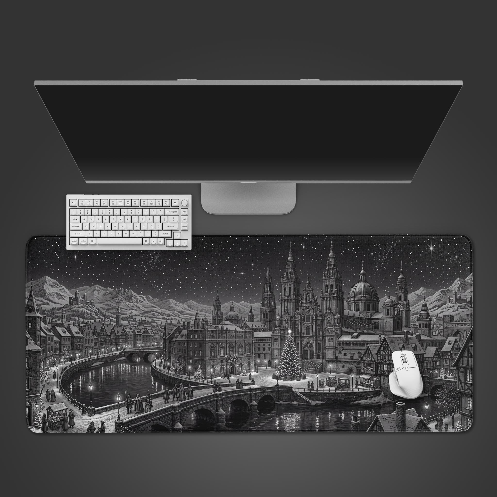 Top-down view of the Winter Spire gaming desk mat featuring a monochrome gothic city design, shown with a white keyboard, mouse, and a large monitor on a dark surface. - Epic Design Pads & Mousepads
